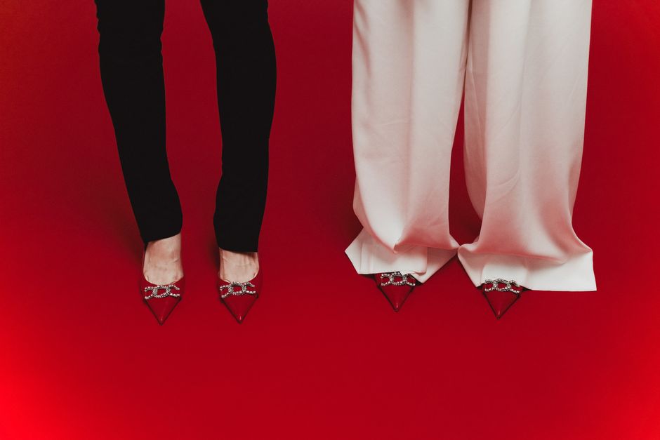 Elegant red shoes with crystal designs paired with black and white pants on red surface