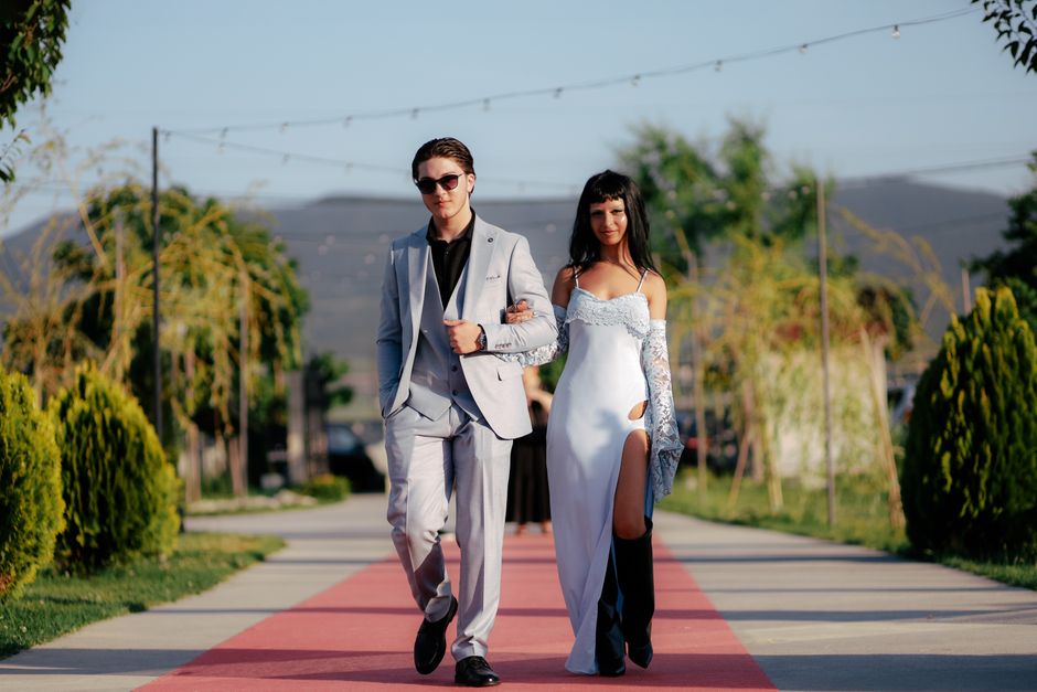 Stylish couple walking confidently on red carpet outdoors in elegant fashion
